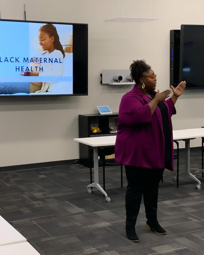 Woman speaking beside a presentation screen during a conference session.