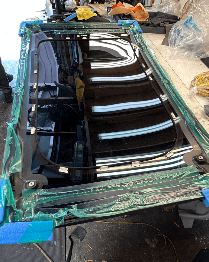 Porsche Taycan panoramic roof glass panel prepped for installation on workbench